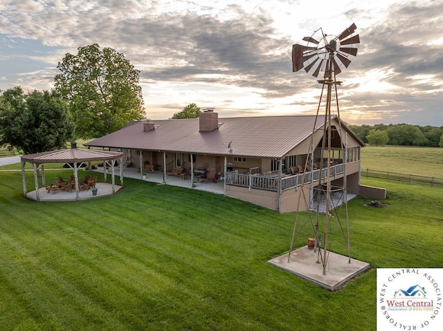 662 W 6th St, Schell City, MO 64783 - rear view of house featuring a patio area, a gazebo, a chimney, and metal roof