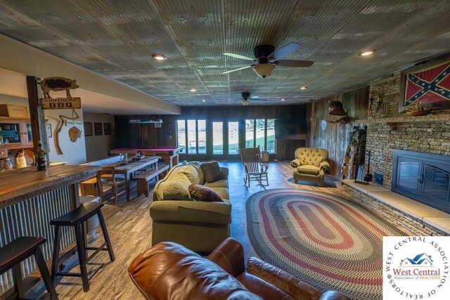 662 W 6th St, Schell City, MO 64783 - living area featuring wood finished floors, a ceiling fan, a fireplace, and a bar