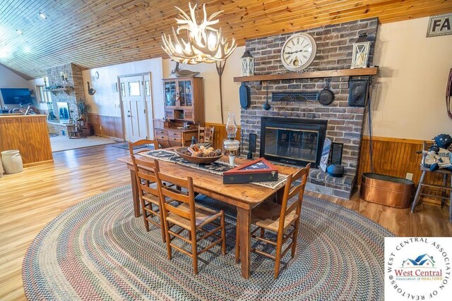662 W 6th St, Schell City, MO 64783 - dining room with wood finished floors, a wainscoted wall, a fireplace, a chandelier, and lofted ceiling