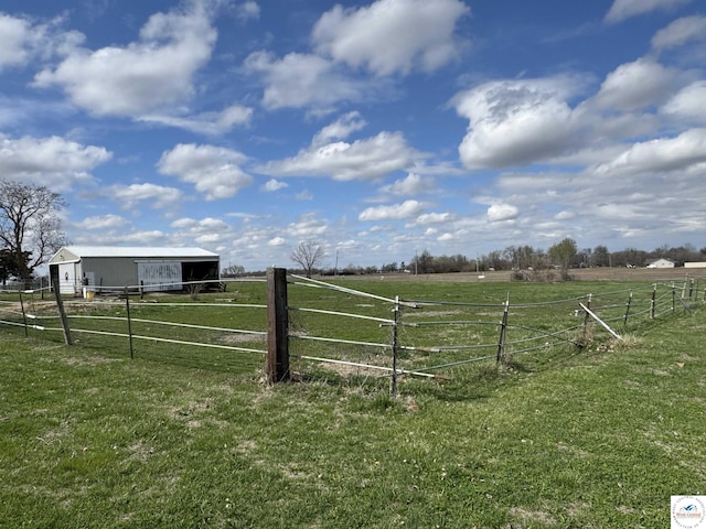 view of yard featuring an outbuilding, an outdoor structure, a rural view, and fence