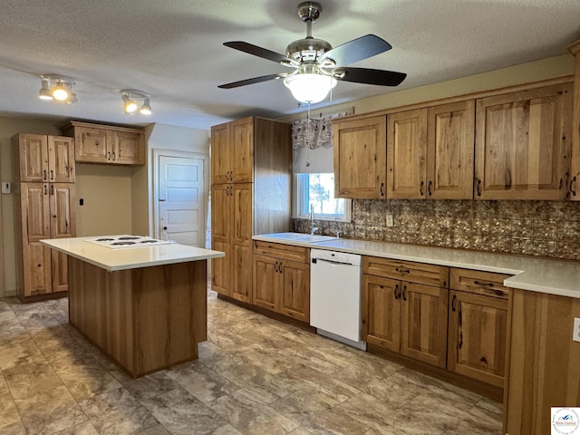 kitchen featuring ceiling fan, white appliances, brown cabinetry, and a sink