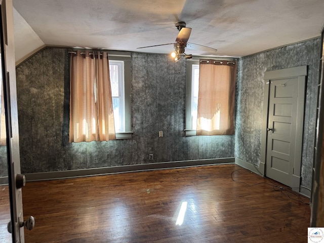 spare room featuring wood finished floors, a ceiling fan, and vaulted ceiling
