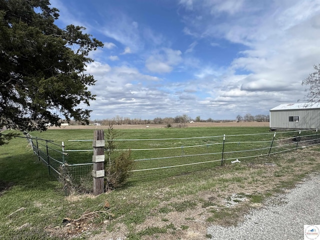view of gate with a rural view, a yard, and fence