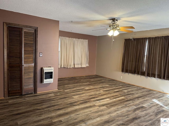 spare room with dark wood-type flooring, heating unit, a ceiling fan, and a textured ceiling