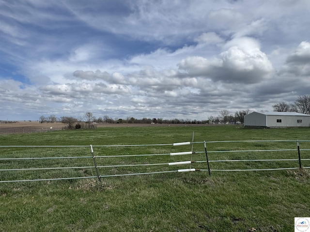 view of gate with fence, a rural view, and a yard