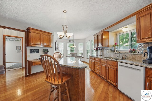 1515 NW Primrose Ln, Blue Springs, MO 64015 - kitchen featuring white dishwasher, a sink, a textured ceiling, a chandelier, and light wood-style flooring