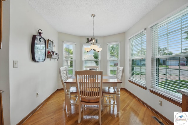 1515 NW Primrose Ln, Blue Springs, MO 64015 - dining room with a chandelier, light wood finished floors, a textured ceiling, and baseboards