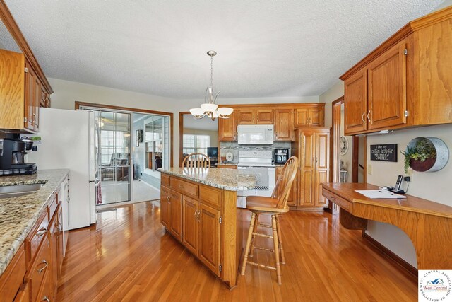 1515 NW Primrose Ln, Blue Springs, MO 64015 - kitchen with white appliances, light wood-style flooring, a kitchen island, a breakfast bar, and brown cabinetry