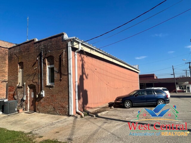 104 E Main St, Cole Camp, MO 65325 - view of home's exterior featuring cooling unit, uncovered parking, and brick siding