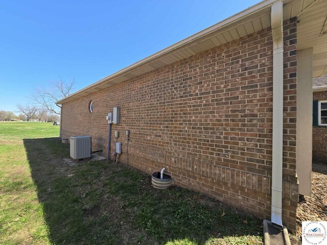 1017 E Trevino Rd, Clinton, MO 64735 - view of side of property featuring brick siding, a yard, and central air condition unit