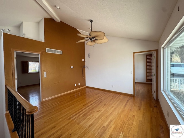 empty room featuring visible vents, plenty of natural light, a ceiling fan, and light wood-style flooring
