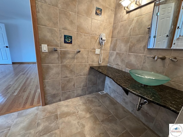 bathroom featuring tile walls and a sink