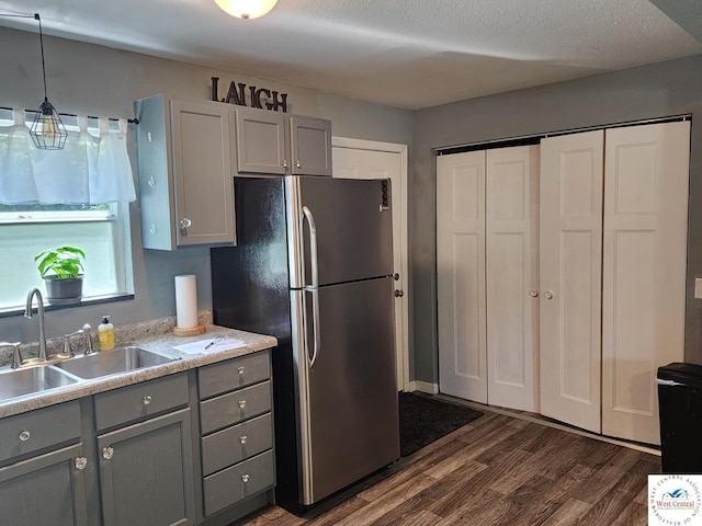 kitchen featuring gray cabinetry, freestanding refrigerator, a sink, dark wood finished floors, and light countertops