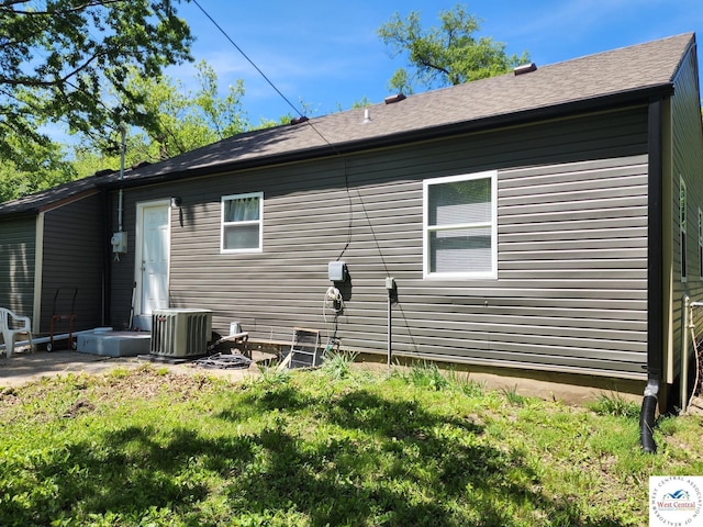 back of property featuring central AC and a yard