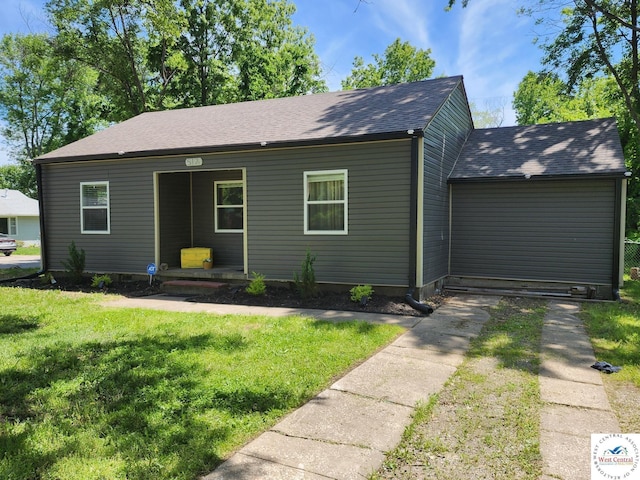 view of front of property featuring a front lawn, covered porch, and a shingled roof