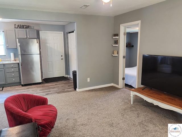 living area with baseboards and light colored carpet
