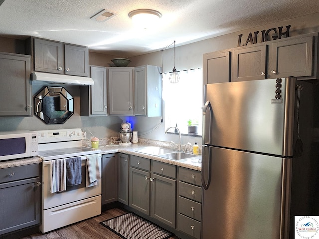 kitchen featuring white appliances, under cabinet range hood, a sink, gray cabinets, and a textured ceiling