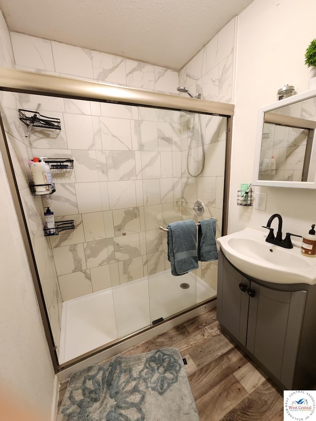 bathroom with a stall shower, wood finished floors, vanity, and a textured ceiling