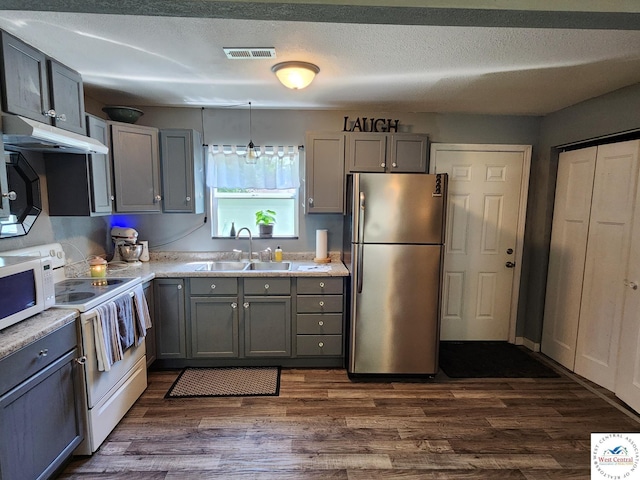 kitchen featuring white appliances, under cabinet range hood, a sink, gray cabinets, and a textured ceiling