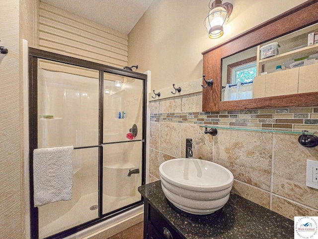 full bath with tile walls, a shower stall, and vanity