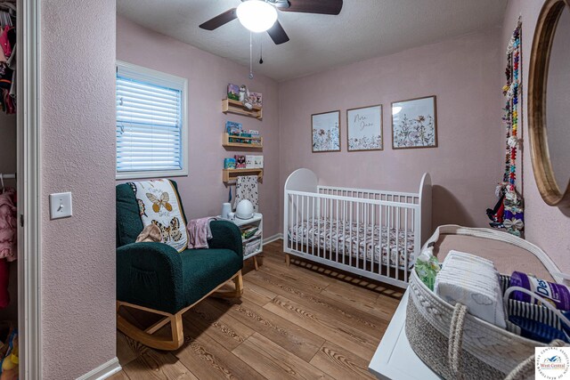 782 SE 250th Rd, Clinton, MO 64735 - bedroom with baseboards, a ceiling fan, a crib, and hardwood / wood-style floors