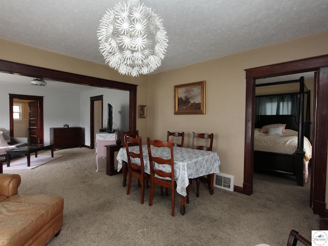 carpeted dining space with baseboards, visible vents, a notable chandelier, and a textured ceiling