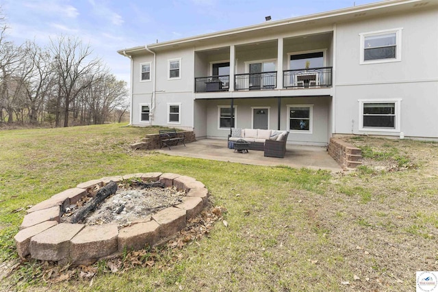 917 N Washboard Rd, Sibley, MO 64088 - rear view of house featuring a balcony, an outdoor living space with a fire pit, a lawn, a patio, and stucco siding