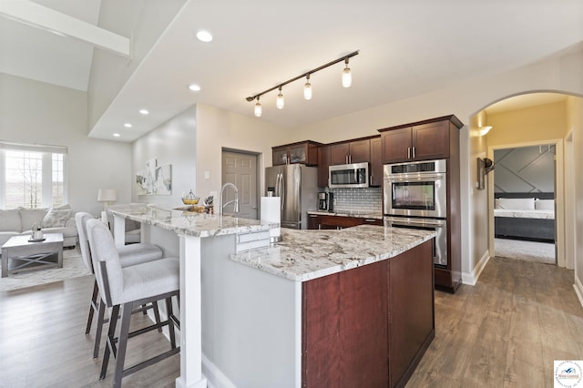 917 N Washboard Rd, Sibley, MO 64088 - kitchen featuring stainless steel appliances, arched walkways, wood finished floors, light stone countertops, and a breakfast bar area