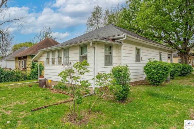 view of home's exterior with a lawn and a shingled roof