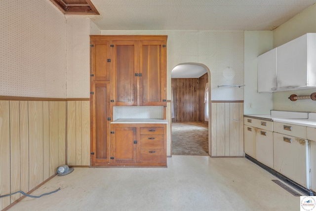 kitchen with wooden walls, light countertops, arched walkways, a wainscoted wall, and visible vents