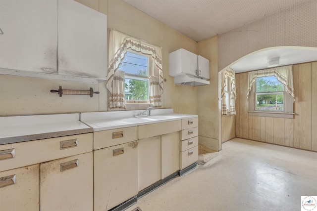 kitchen featuring a sink, arched walkways, light countertops, and a wealth of natural light