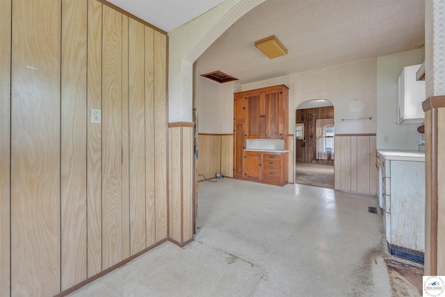 interior space with arched walkways, wainscoting, and wooden walls