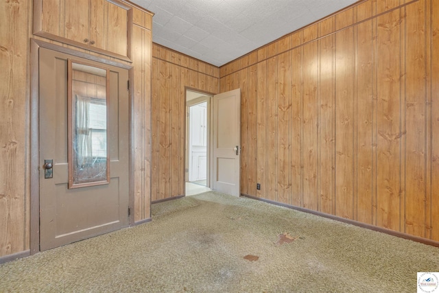 carpeted empty room featuring wooden walls