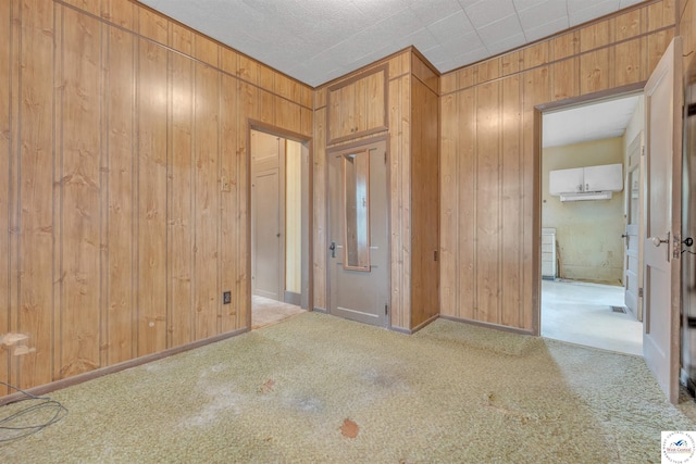 unfurnished bedroom featuring carpet and wooden walls