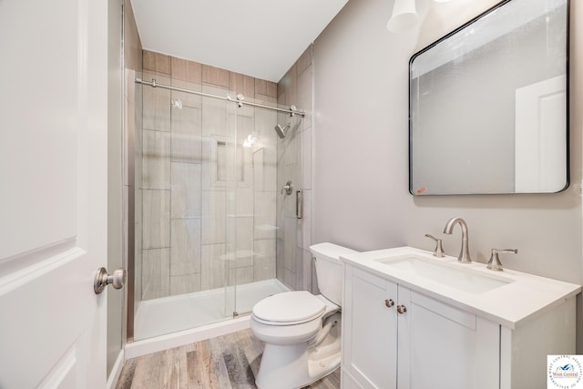 bathroom featuring toilet, a shower stall, wood finished floors, and vanity