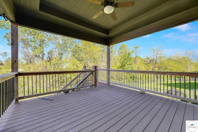 wooden terrace with a ceiling fan and view of wooded area