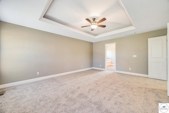 spare room featuring a tray ceiling, a ceiling fan, carpet floors, baseboards, and crown molding