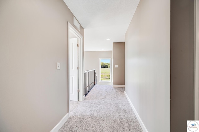 hallway with light colored carpet, an upstairs landing, and baseboards