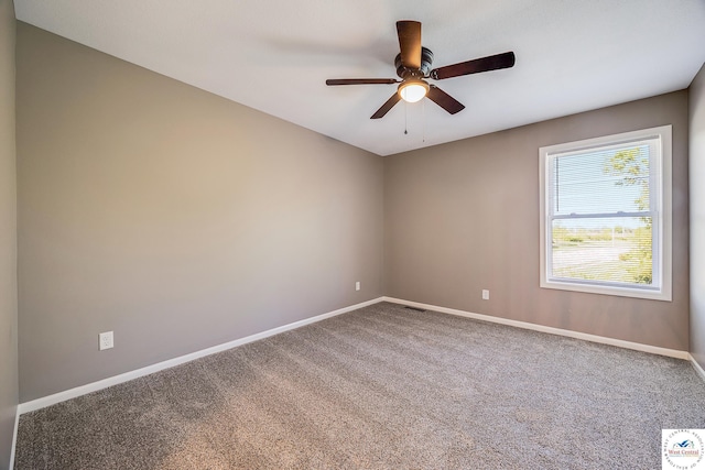 carpeted spare room featuring baseboards and a ceiling fan