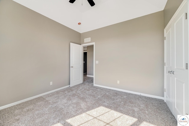 unfurnished bedroom featuring carpet, baseboards, ceiling fan, and a towering ceiling