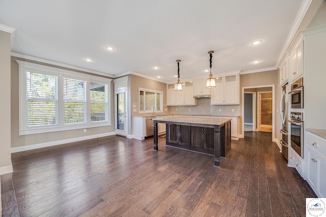 kitchen with appliances with stainless steel finishes, a center island, dark wood-style flooring, backsplash, and baseboards