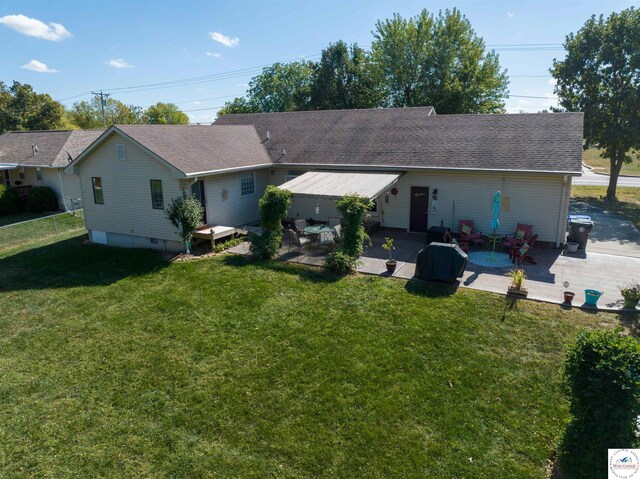 rear view of property featuring fence, a shingled roof, a yard, and a patio area