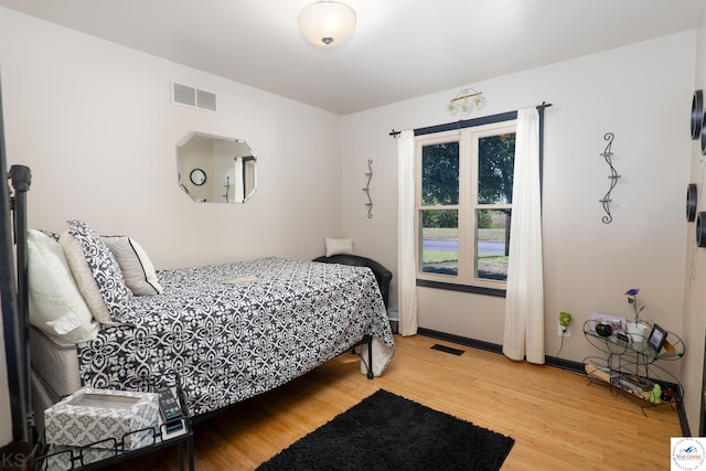 bedroom with visible vents, wood finished floors, and baseboards