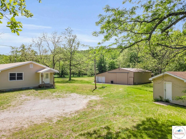 20390 Kindle Rd, Warsaw, MO 65355 - view of green lawn with an outbuilding, a garage, and a forest view
