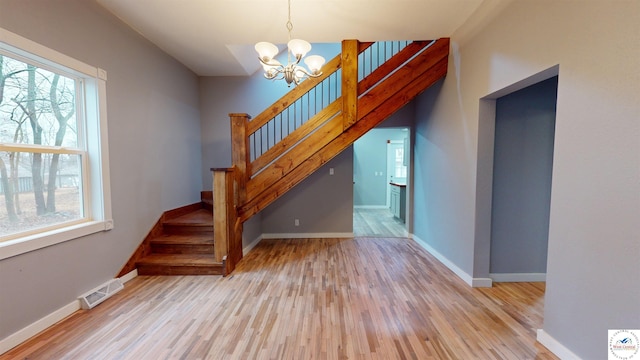 607 E Benton St, Windsor, MO 65360 - staircase featuring visible vents, a notable chandelier, wood finished floors, and a healthy amount of sunlight
