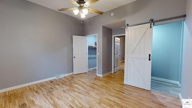 607 E Benton St, Windsor, MO 65360 - unfurnished bedroom with visible vents, baseboards, a barn door, and light wood-type flooring