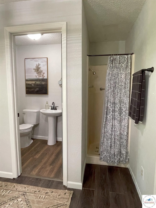 22756 Hickory Chapel Ave, Lincoln, MO 65338 - bathroom featuring a textured ceiling, toilet, wood finished floors, a shower stall, and baseboards