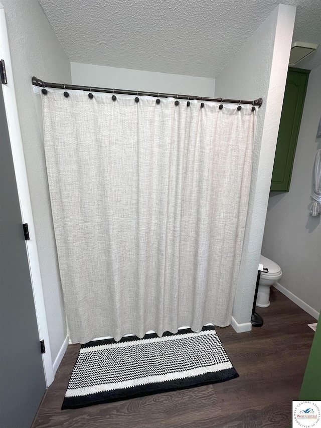 22756 Hickory Chapel Ave, Lincoln, MO 65338 - bathroom featuring toilet, wood finished floors, a textured ceiling, baseboards, and curtained shower