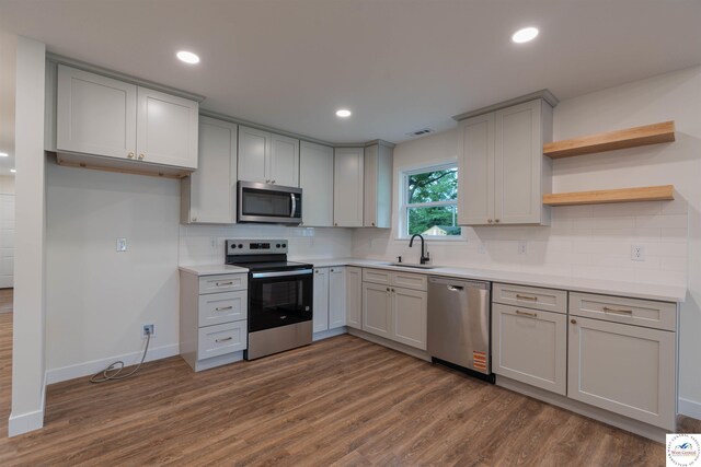 1504 E 7th St, Sedalia, MO 65301 - kitchen featuring appliances with stainless steel finishes, dark wood-type flooring, tasteful backsplash, gray cabinets, and light countertops