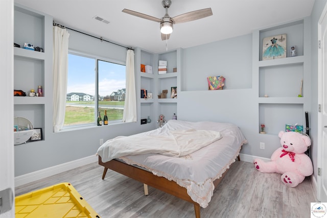 bedroom featuring a ceiling fan, visible vents, wood finished floors, and baseboards